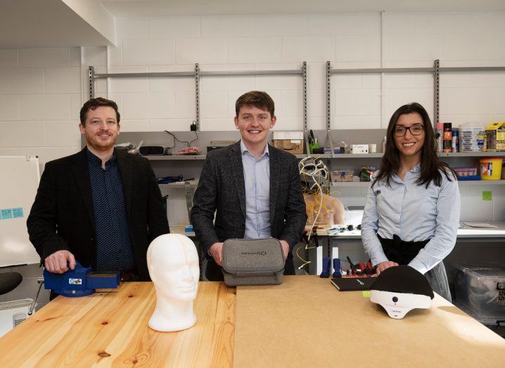 Two men and a woman stand behind a table in what looks like an office space. All three are co-founders of Luminate Medical.