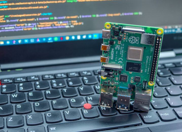 A computer chip on top of a keyboard laptop, with code visible on the laptop screen.