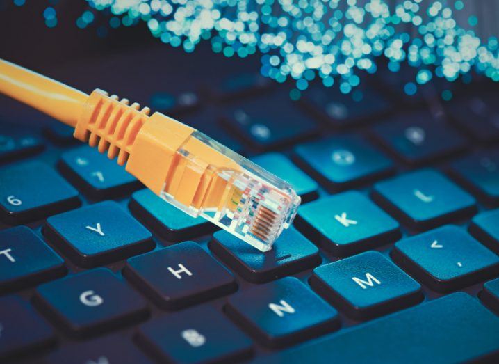 An internet cable on a keyboard with small lit up wires visible at the top of the image. Used to represent fibre broadband.