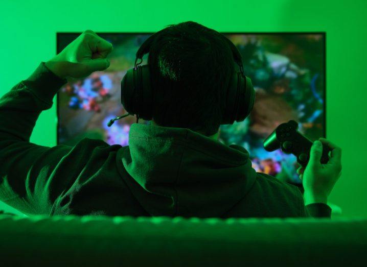 Gamer celebrating victory with a gesture. He is illuminated with green light.