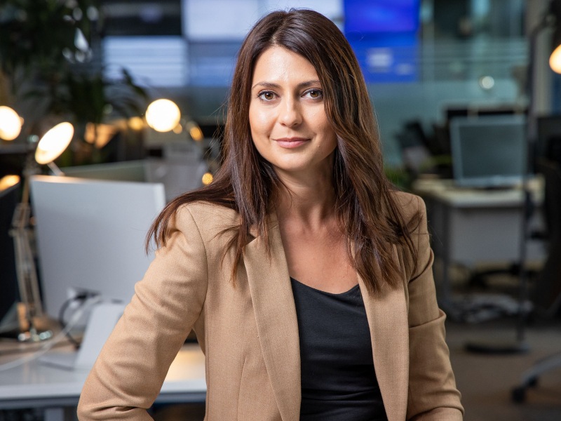 Raluca Saceanu stands in an office wearing a suit.