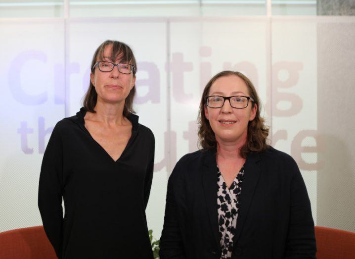 Two women, Ann O’Dea and Sheila McBreen, stand together while smiling at the camera. The wall behind them says Creating the Future.